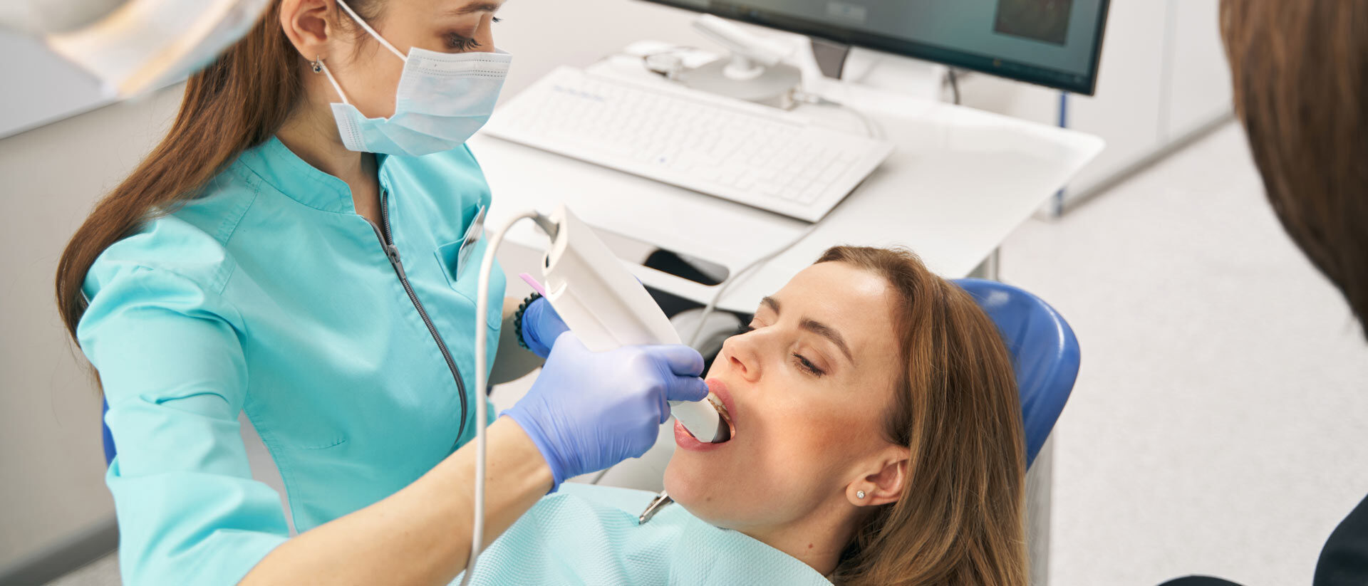 Zahnärztin erstellt eine digitale Abformung mit dem Intraoralscanner, der Scan erscheint am Monitor